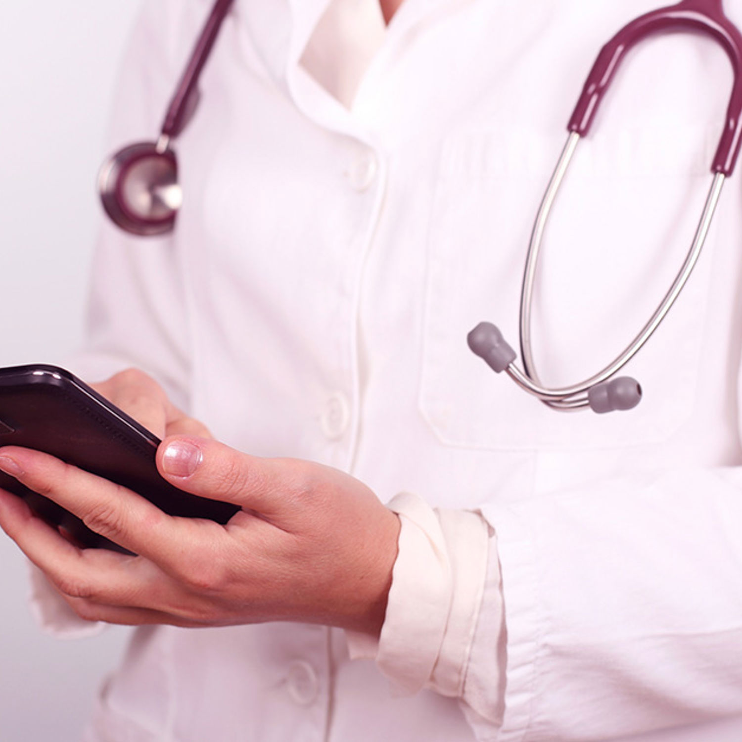Vårdpersonal med stetoskop kollar i telefonen