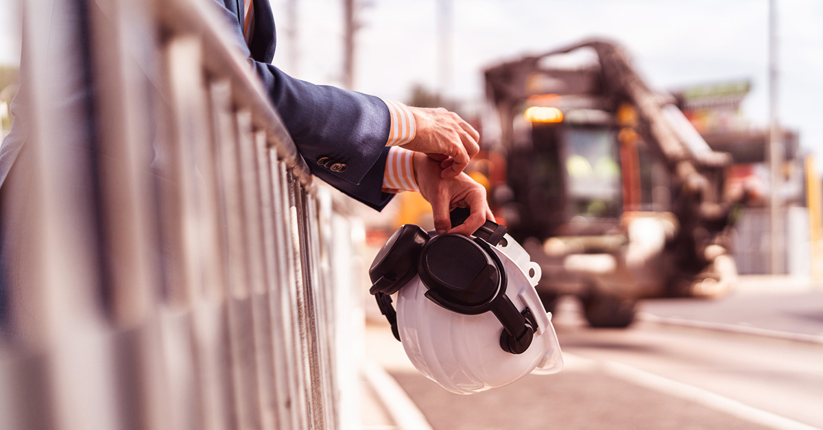 Person på byggarbetsplats lutar sig över staket