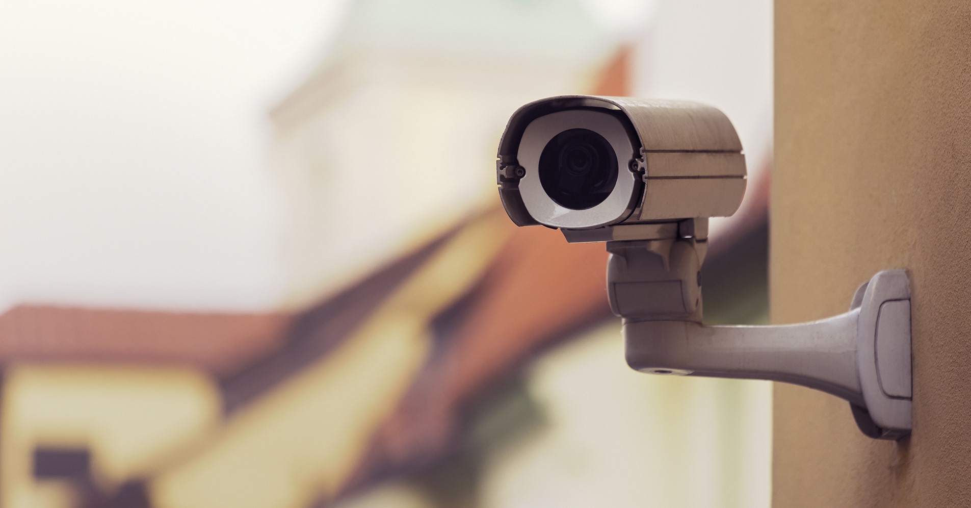 En kamera som är monterad på en gul fasad till ett lägenhetshus.